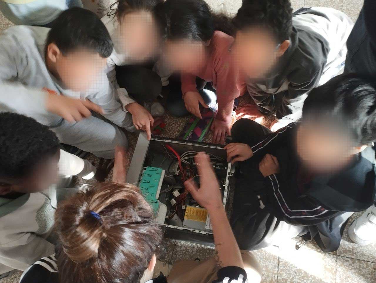 An open computer with kids looking inside while someone is explaining